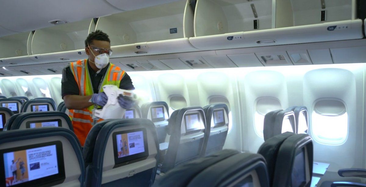Un empleado de Delta Air Lines sanitiza el interior de un avión con un rociador electrostático.