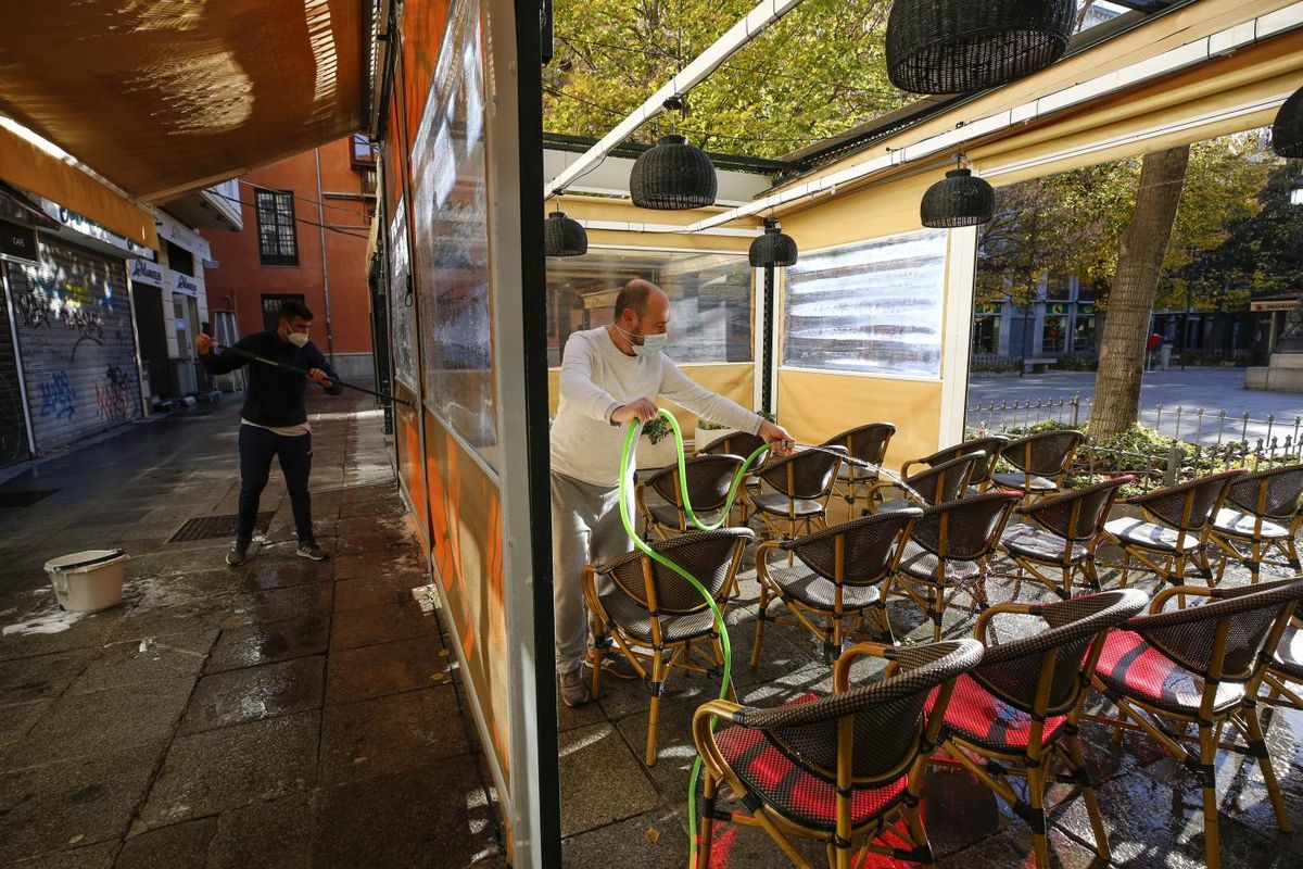 Trabajadores de un bar poniendo la terraza del local.