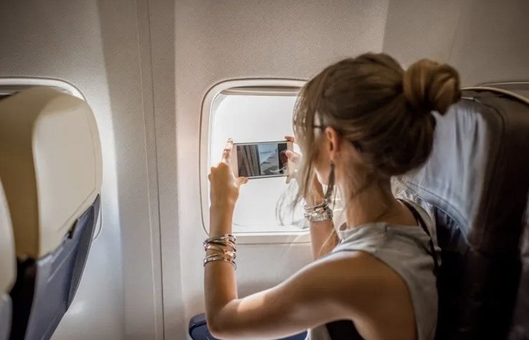 Una pasajera graba un vídeo con su teléfono en un avión.