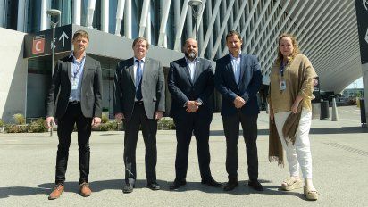 Autoridades de AA2000 y de Genneia posan tras la firma del acuerdo, frente a la nueva terminal de partidas del aeropuerto de Ezeiza.