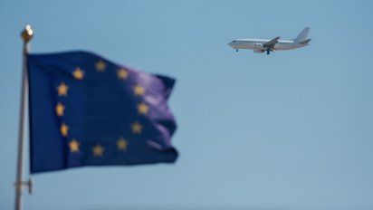 Avion en segundo plan frente a una bandera de la Unión Europea.