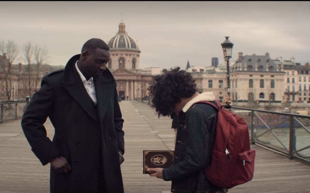 En la explanada Assane le regala a su hijo Raoul,  el libro de Arsène Lupin que a su vez le había regalado su padre.