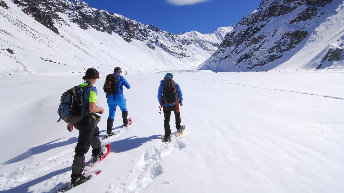 Con raquetas especiales para nieve, se avanza suavemente por laderas abiertas, rodeados de montañas nevadas y bajo la imponente presencia del volcán San José.