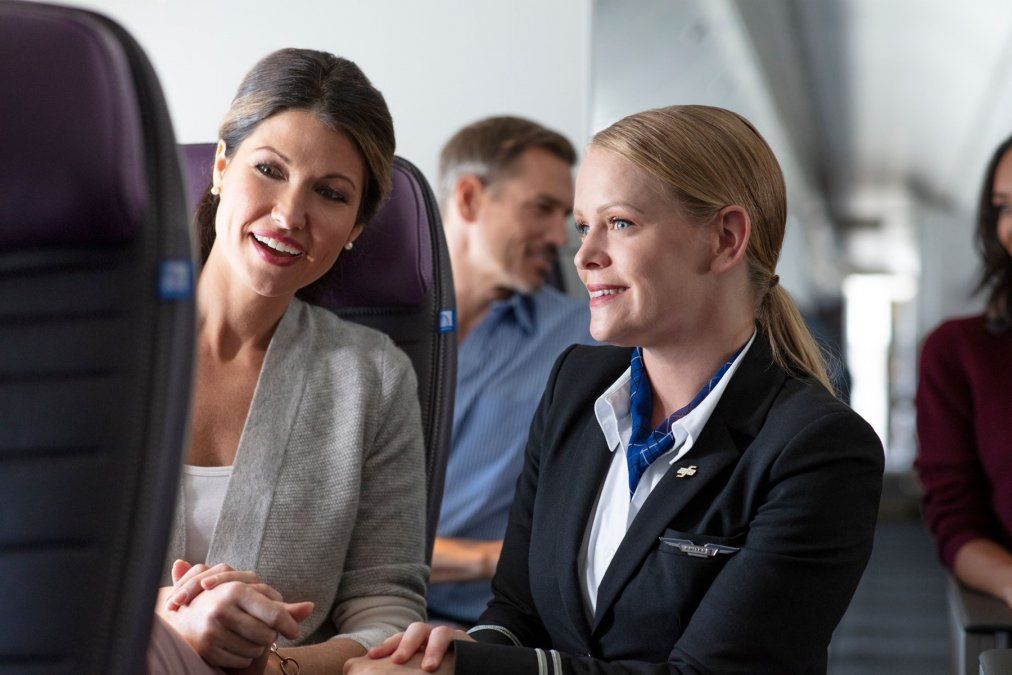 Un TCP de United Airlines asesora a una pasajera sobre cómo funciona la pantalla individual.